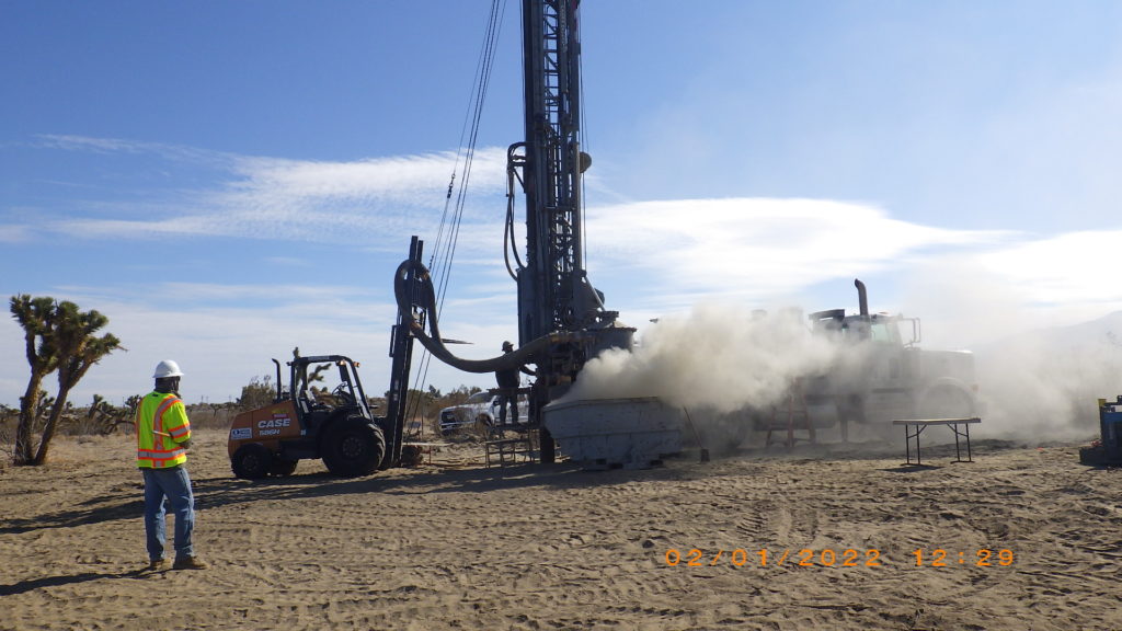 Air rotary casing hammer drill rig in field with dust blowing